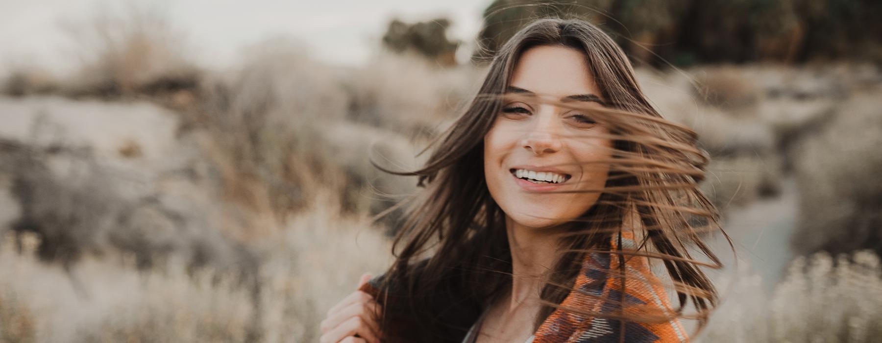 a woman smiling with her hands together